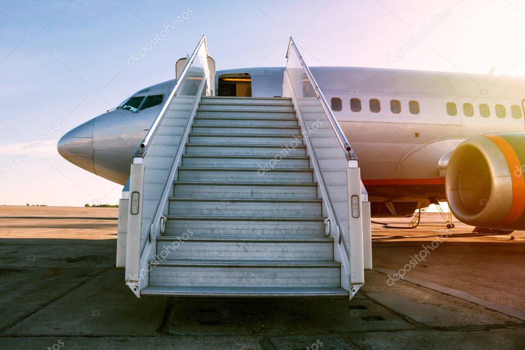 Passenger airplane with a boarding steps in the morning sun