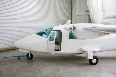 Çift motorlu hafif uçak ile açık kapı hangarda yüksek kanatlı