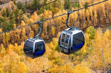 Gondola lifts to the mountain in the autumn forest clipart