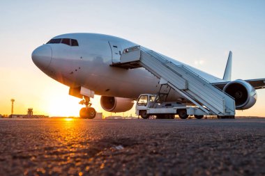 Akşam güneşin Havaalanı apron yatılı bir merdiven ile beyaz geniş gövdeli yolcu uçak