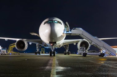 Beyaz geniş gövdeli yolcu uçak gece Havaalanı önlük, yatılı birkaç adım önden görünümü