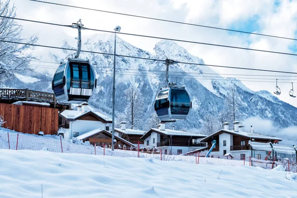 Gondola lifts, village and high mountain range on a clear sunny day in winter