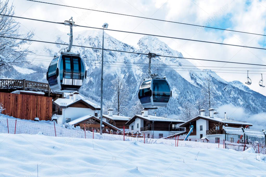 Gondola lifts, village and high mountain range on a clear sunny day in winter