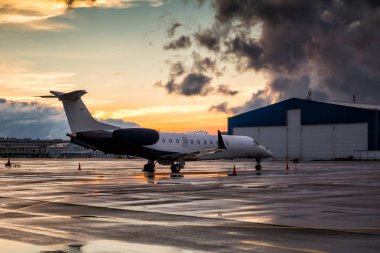 Hangar yakınında Havaalanı apron yağmur sonra gün batımı iş Jet