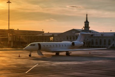 Terminalde yakın havaalanı apron altın akşam ışığında bir merdiven ile açık kapı ile iş uçağı