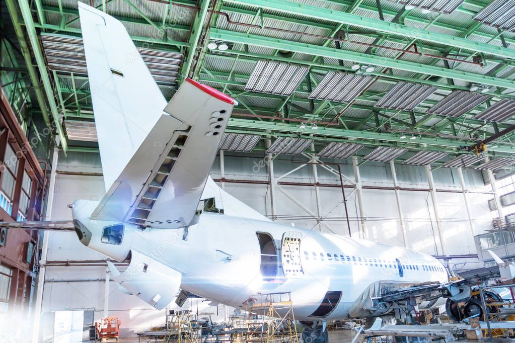Passenger aircraft under maintenance in the hangar. Checking mechanical systems for flight operations. Close-up view of the tail of the airplane
