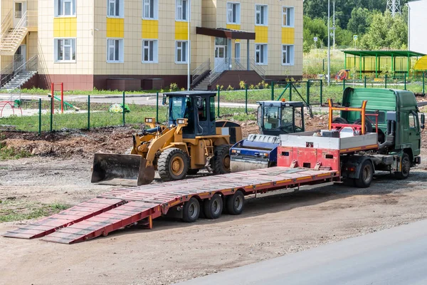 Düşük yükleyicili kamyon, yol silindiri ve tekerlekli traktör tamir ediliyor.