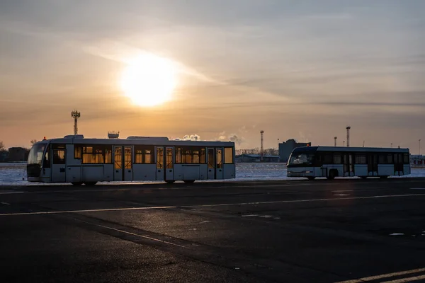 Two empty airport shuttle buses in a cold winter evening