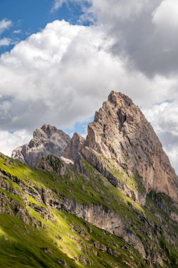 Geisler Grubu 'ndan Gran Fermeda ve Sass Rigais' in dramatik dağ zirvesi. Puez-Odle doğa parkındaki Odle grubu, İtalyan Dolomitler Alpleri 'ndeki Val Gardena' da parçalı bulutlu bir gökyüzüne karşı hızla yükseliyor.