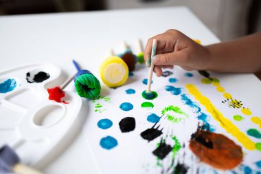 Beyaz tuvaldeki sünger fırçalarını kullanarak parlak renklerde çocuk resimleri. Yüksek kalite.