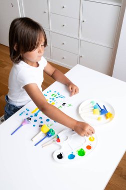 Genç beyaz bir çocuk evde fırçayla yaratıcı boya aktivitesi yapıyor. Yüksek kalite.