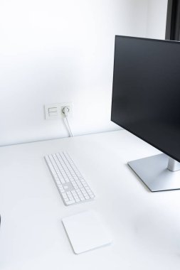 Modern monitörü, klavyesi, beyaz masasında fare altlığı olan minimalist çalışma alanı. Yüksek kalite.