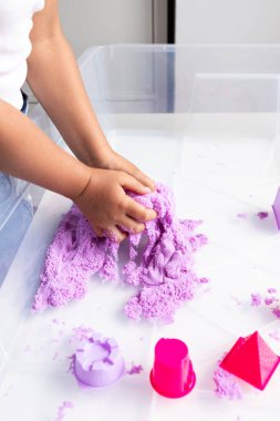 Çocuk tepside mor kinetik kumla oynuyor. Yüksek kalite.