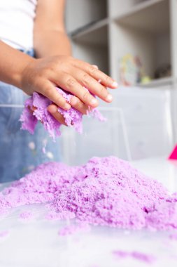 Child playing with colorful kinetic sand at home. High quality.