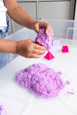 Çocuk içeride mor kinetik kumla oynuyor. Yüksek kalite.