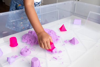 Child playing with colorful kinetic sand and molds. High quality.
