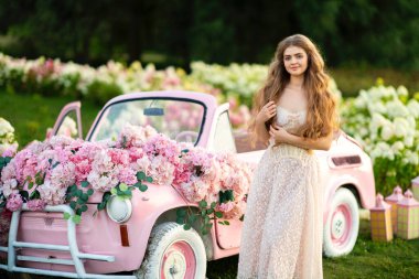 Klasik şık elbiseli güzel bir kadın parkta ortancalar arasında poz veriyor.