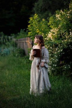 Kırsalda yasemin çiçekleriyle poz veren eski püskü elbiseli güzel bir kadın.