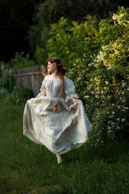 Kırsalda yasemin çiçekleriyle poz veren eski püskü elbiseli güzel bir kadın.