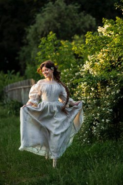 Kırsalda yasemin çiçekleriyle poz veren eski püskü elbiseli güzel bir kadın.