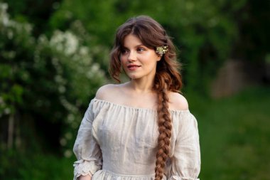 Kırsalda yasemin çiçekleriyle poz veren eski püskü elbiseli güzel bir kadın.