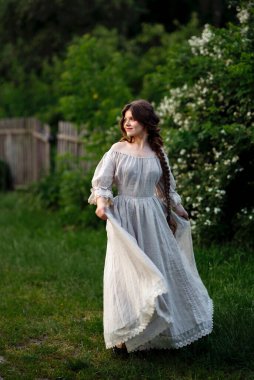 Kırsalda yasemin çiçekleriyle poz veren eski püskü elbiseli güzel bir kadın.