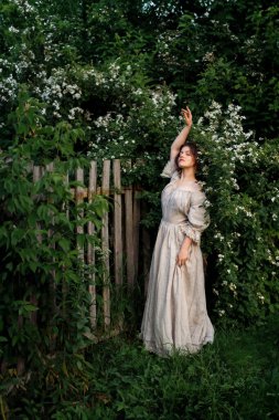 Kırsalda yasemin çiçekleriyle poz veren eski püskü elbiseli güzel bir kadın.