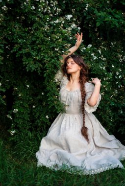 Kırsalda yasemin çiçekleriyle poz veren eski püskü elbiseli güzel bir kadın.