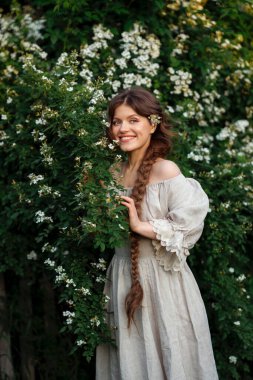 Kırsalda yasemin çiçekleriyle poz veren eski püskü elbiseli güzel bir kadın.