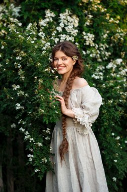 Kırsalda yasemin çiçekleriyle poz veren eski püskü elbiseli güzel bir kadın.