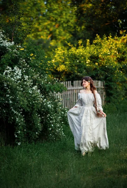 Kırsalda yasemin çiçekleriyle poz veren eski püskü elbiseli güzel bir kadın.
