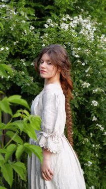 Kırsalda yasemin çiçekleriyle poz veren eski püskü elbiseli güzel bir kadın.