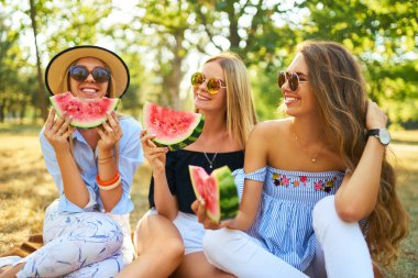 Eğleniyor üç güzel kız parkta karpuz yeme. Mükemmel güneşli havalarda. Güzel resimler. Süper ruh hali. Yaz konsepti.