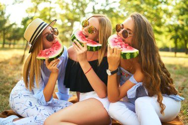 Eğleniyor üç güzel kız parkta karpuz yeme. Mükemmel güneşli havalarda. Güzel resimler. Süper ruh hali. Yaz konsepti.