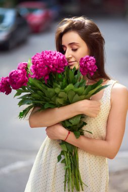 Bahar / yaz stili. Pions bir buket ile bir güzel bahar içinde güzel genç esmer kadın. Güzel Spring Sokağı. Moda bahar yaz fotoğraf.