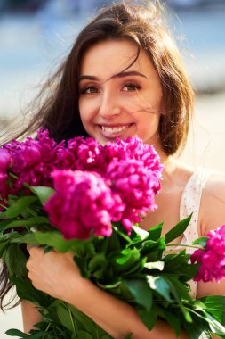 Bahar / yaz stili. Pions bir buket ile bir güzel bahar içinde güzel genç esmer kadın. Güzel Spring Sokağı. Moda bahar yaz fotoğraf.