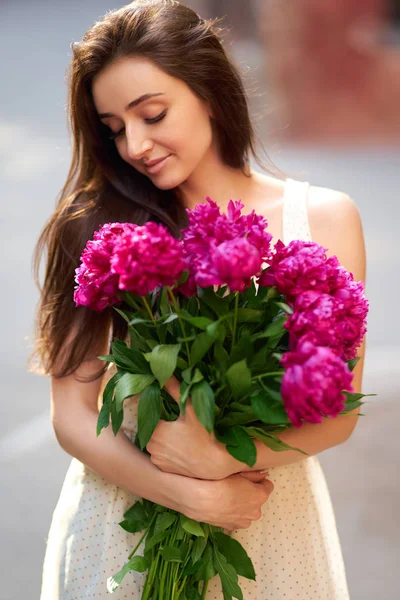 Spring / Summer Style. Beautiful Young Brunette Woman In A Nice Spring Dress With A Bouquet Of Pions. Beautiful Spring Street. Fashion Spring Summer Photo.