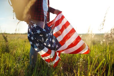 4 Temmuz. Amerikan Flag.Patriotic tatil. Amerika bayrağı ile seyahat. Adam bir şapka, bir sırt çantası, bir tişört ve kot pantolon giyiyor. Güzel gün batımı ışık. Amerikan tarzı. 