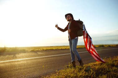 4 Temmuz. Amerikan Flag.Patriotic tatil. Amerika bayrağı ile seyahat. Adam bir şapka, bir sırt çantası, bir tişört ve kot pantolon giyiyor. Güzel gün batımı ışık. Amerikan tarzı. 