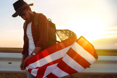 4 Temmuz. Amerikan Flag.Patriotic tatil. Amerika bayrağı ile seyahat. Adam bir şapka, bir sırt çantası, bir tişört ve kot pantolon giyiyor. Güzel gün batımı ışık. Amerikan tarzı. 