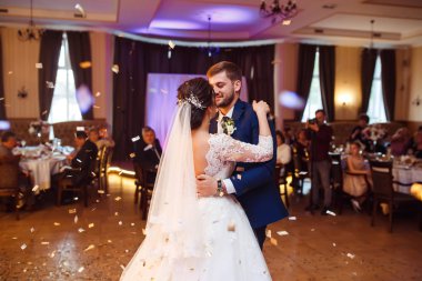 Mutlu gelin ve damat ve güzel ışık ve arka plan üzerinde kişi ile zarif restoranda düğün ilk dansları,