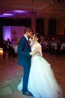 Mutlu gelin ve damat ve güzel ışık ve arka plan üzerinde kişi ile zarif restoranda düğün ilk dansları,