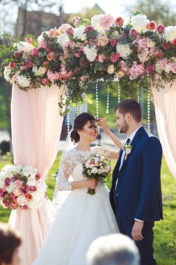 Gelin ve damat düğün töreninde çok güzel görünüyorlar. Düğün çifti dışarıda romantik anlar yaşıyor.
