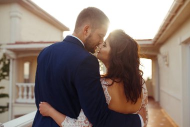 Güzel gelin ve damat hoşlanıyoruz. onların evlilik kutlama mutlu romantik genç bir çift. Aşıkların seksi öpüşme şık çift portre kadar kapatın. Düğün kavramı. günbatımı ışığı