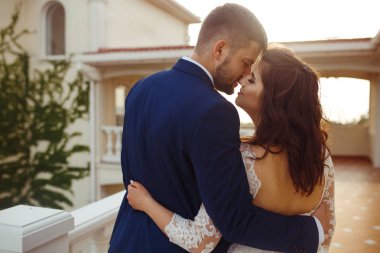 Güzel gelin ve damat hoşlanıyoruz. onların evlilik kutlama mutlu romantik genç bir çift. Aşıkların seksi öpüşme şık çift portre kadar kapatın. Düğün kavramı. günbatımı ışığı