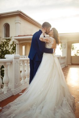 Güzel gelin ve damat hoşlanıyoruz. onların evlilik kutlama mutlu romantik genç bir çift. Aşıkların seksi öpüşme şık çift portre kadar kapatın. Düğün kavramı. günbatımı ışığı