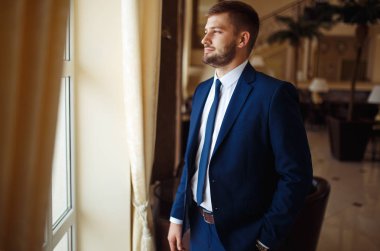 gülümseyen ve otelin salonunda gelin için bekleyen düğün smokin, damat. Zengin düğün gününde damat. Zarif damat kostüm ve Papyon. İlik tutan takım elbiseli damat.