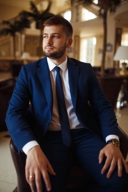 gülümseyen ve otelin salonunda gelin için bekleyen düğün smokin, damat. Zengin düğün gününde damat. Zarif damat kostüm ve Papyon. İlik tutan takım elbiseli damat.