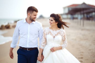 Güzel gelin ve damat sahilde yürüyüş hoşlanıyoruz. onların evlilik kutlama mutlu romantik genç bir çift. Aşıkların seksi öpüşme şık çift portre kadar kapatın. Düğün kavramı.