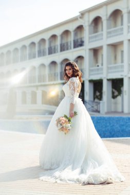 Beyaz bir gelinlikle çok güzel bir gelin şu sedyeyi günbatımı ışığı güzel bir kemer karşı keyif alıyor. İyi bir ruh hali, harika bir atmosfer. Düğün kavramı.